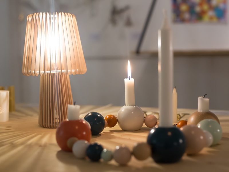 Festivités de Noël à Sélestat Décoration de Noël artisanale avec une lampe en bois lamellé et des bougies disposées sur une couronne de boules en bois colorées.